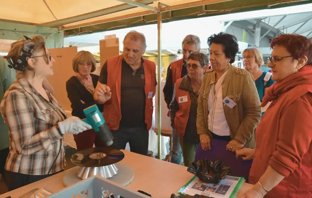 Plusieurs personnes rassemblées autour d'un table observent le séchage d'un vinyle